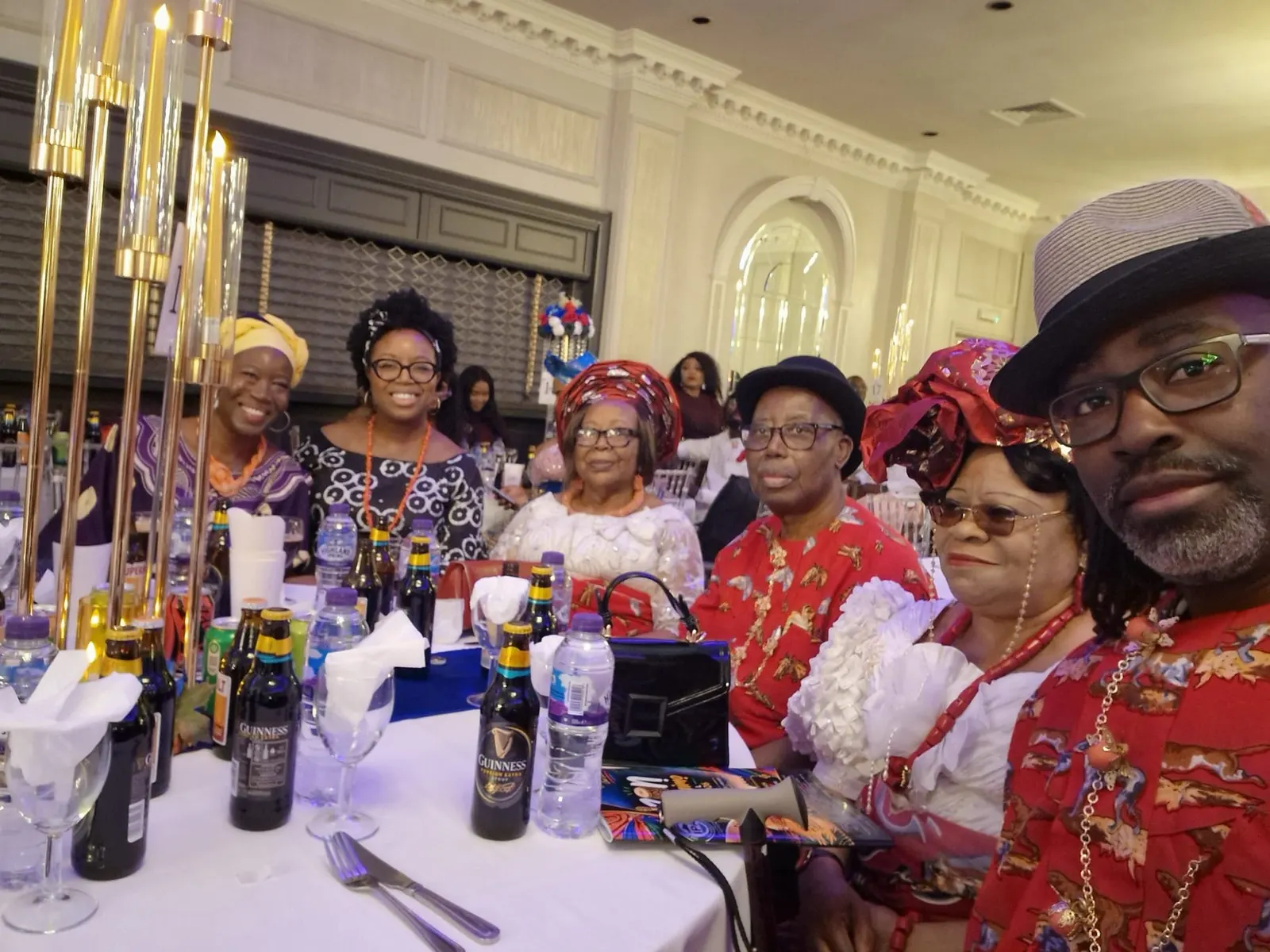 Members in red and white traditional attire with coral beads at a gala table