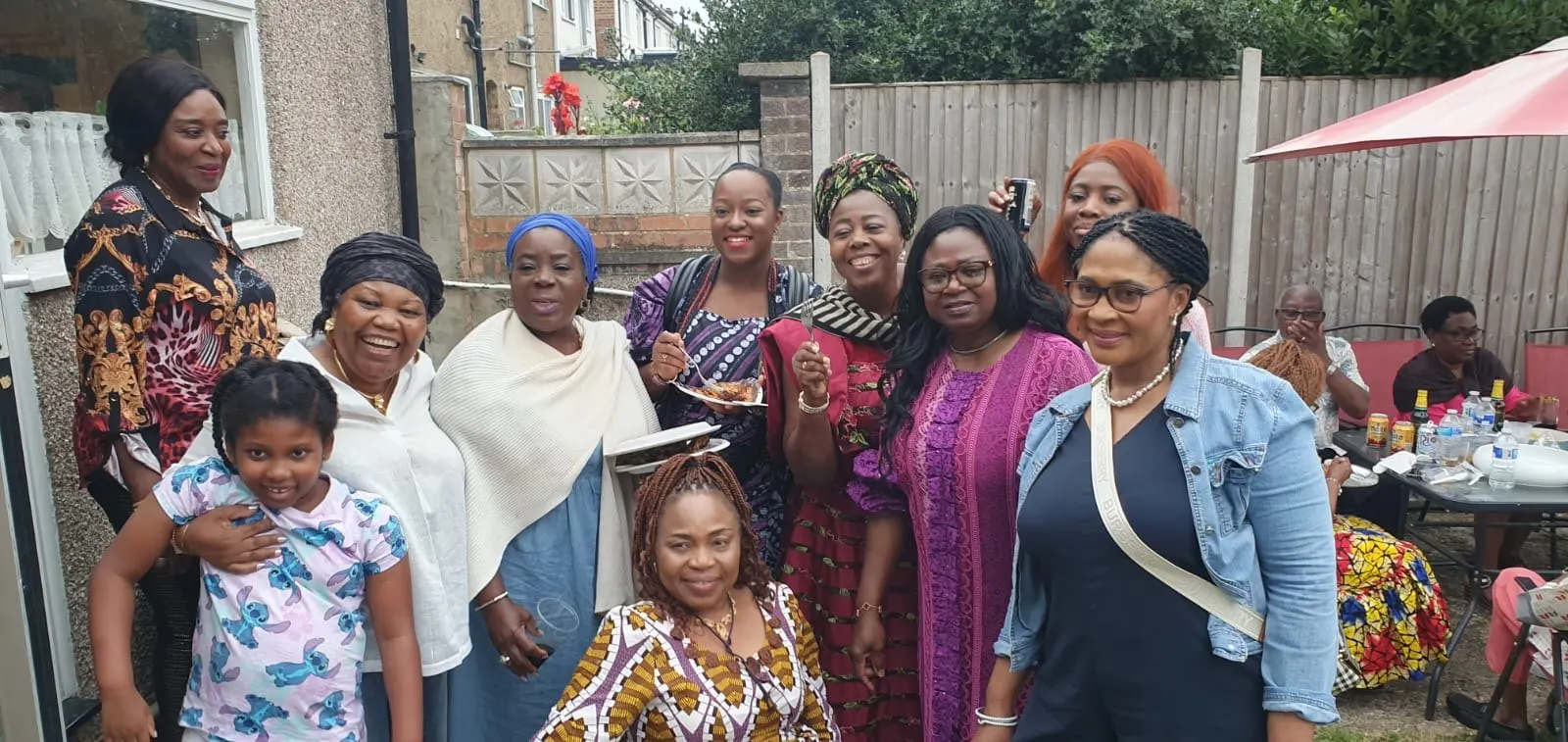 A large group of women and a child posing together in a garden