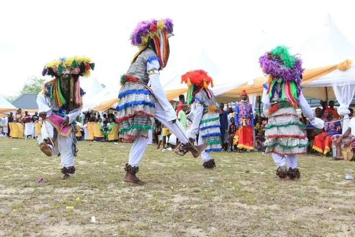 Masquerade dancers in feathered headpieces performing at home