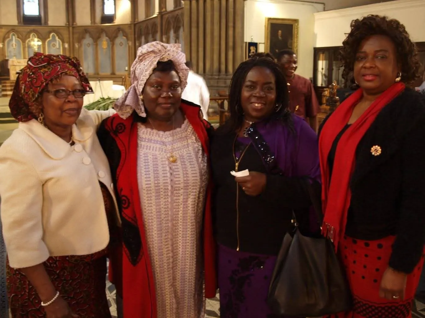 Four women in colourful traditional outfits posing in a church