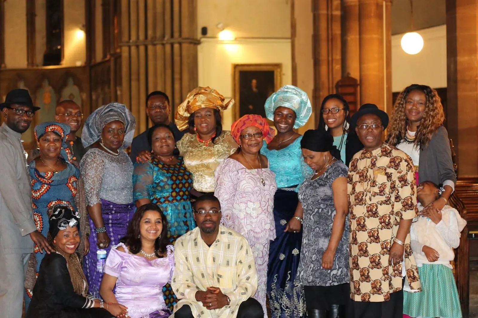 A large group in colourful traditional outfits posing together in a church
