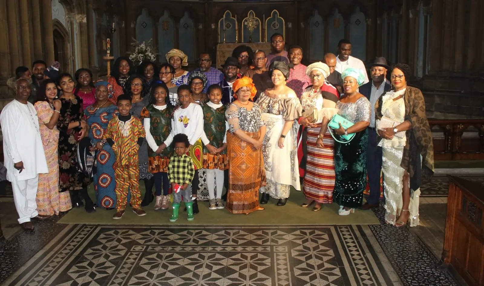 A large group of adults and children posing in front of a church altar